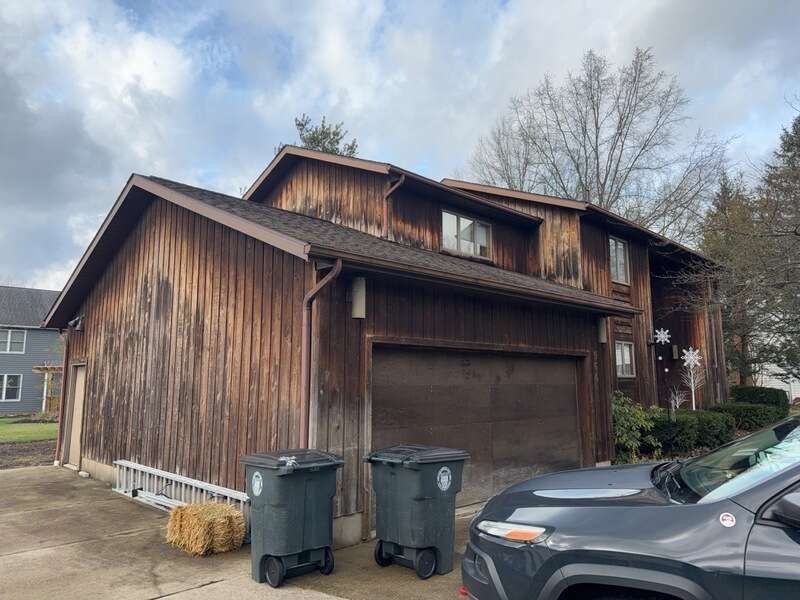 garage wing with weathered dark wood siding before remodel
