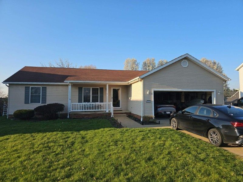 ranch home with tan siding and brown shingle roof before remodel