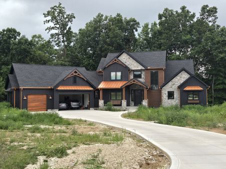 black board and batten home with copper metal roof accents and stone details