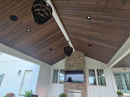 covered patio with a stone fireplace and vaulted wood plank ceiling